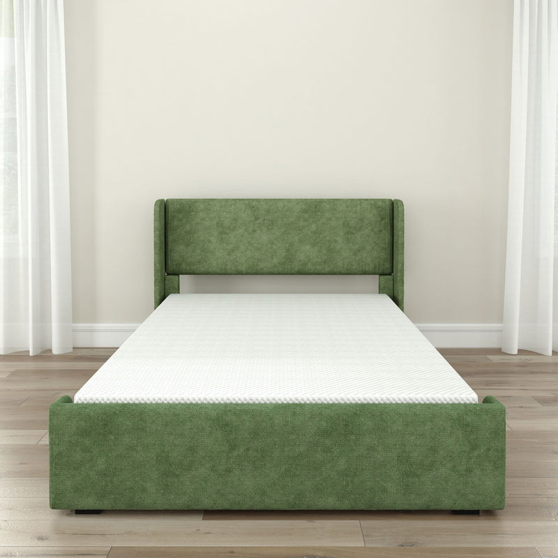 Green upholstered platform bed with padded headboard and white mattress in a modern minimalist bedroom with hardwood floors, neutral walls, and sheer curtains