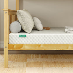 Gel memory foam mattress on wooden bed frame with cushions and folded towels.