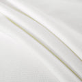 Close-up of folded white textured knit fabric with subtle waffle pattern, soft breathable cotton blend for bedding and apparel