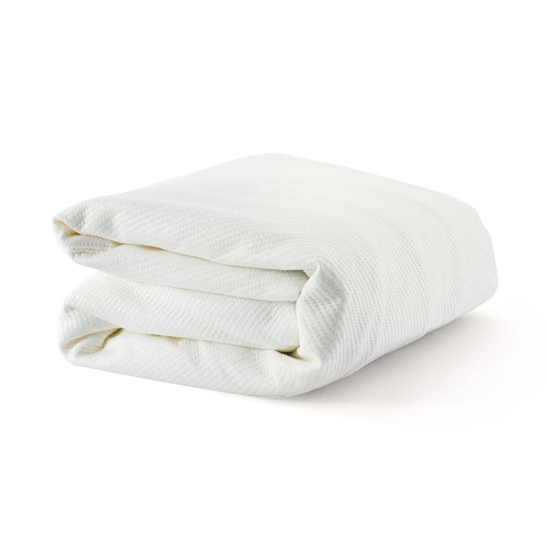 Folded white waffle-knit cotton throw blanket on white background, soft breathable bed and sofa blanket for home decor