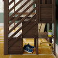 Dark walnut wooden bunk bed staircase with built-in cubby storage, blue sneakers, yellow wire laundry basket and potted succulent in a sunlit green-walled kids' bedroom