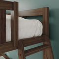 Close-up of dark wood bunk bed ladder and guardrail with white bedding against teal wall — modern rustic bedroom furniture detail