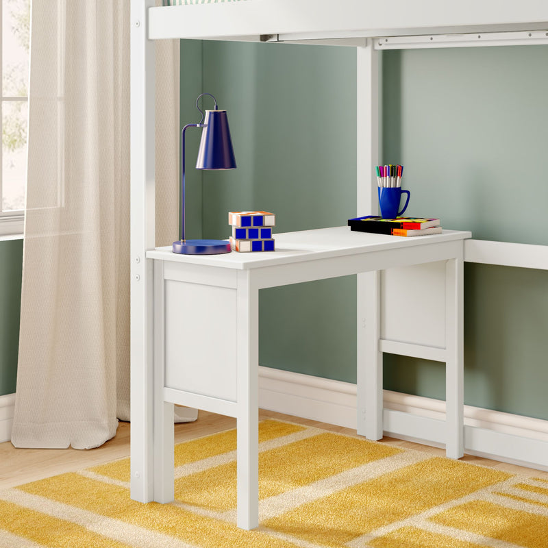 White kids’ study desk tucked under a loft bed with a blue desk lamp, stacked puzzle cube, mug of colorful markers and books against a green wall and yellow striped rug