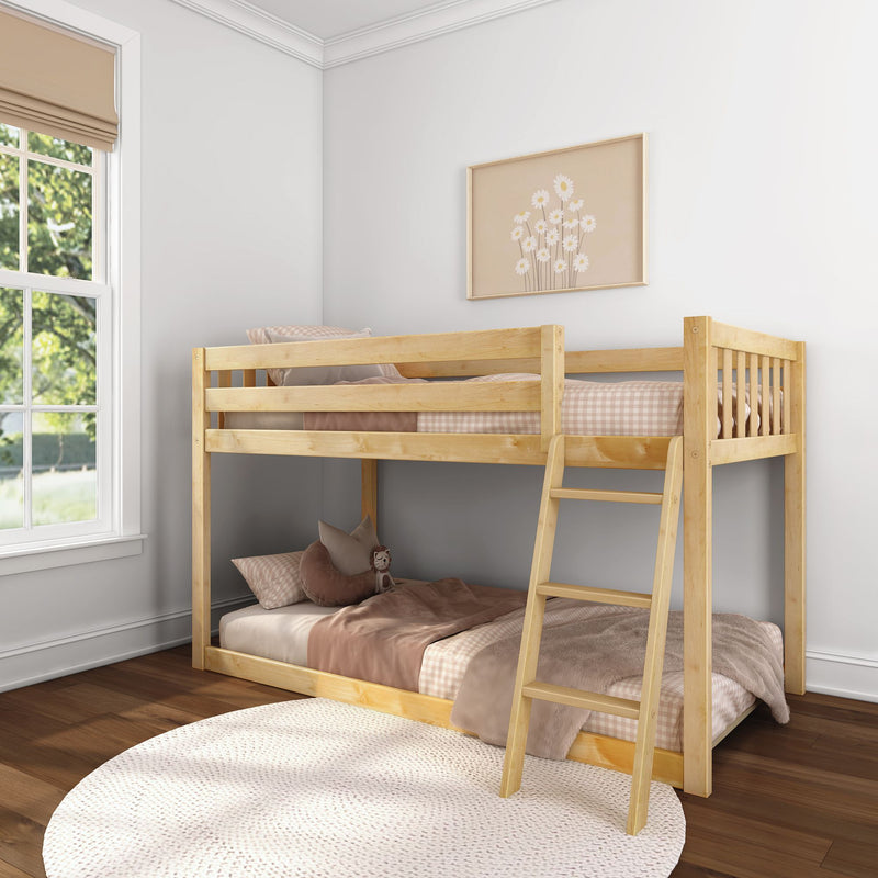 Natural wood twin bunk bed with ladder in sunlit children's bedroom, pink-beige bedding, round rug and floral wall art