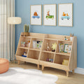 Light wood children's bookshelf and toy storage unit with open cubbies in a blue nursery, styled with framed animal car prints, a floor lamp, plush rug and organized kids room decor.