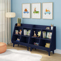 Navy blue children's bookshelf with cubby toy storage and books in a light-blue nursery, three framed animal car prints, floor lamp, orange pouf and white rug