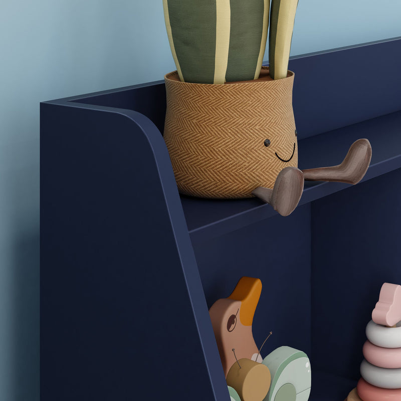 Navy blue kids shelf with smiling woven planter, wooden duck pull toy and pastel stacking rings — modern nursery decor