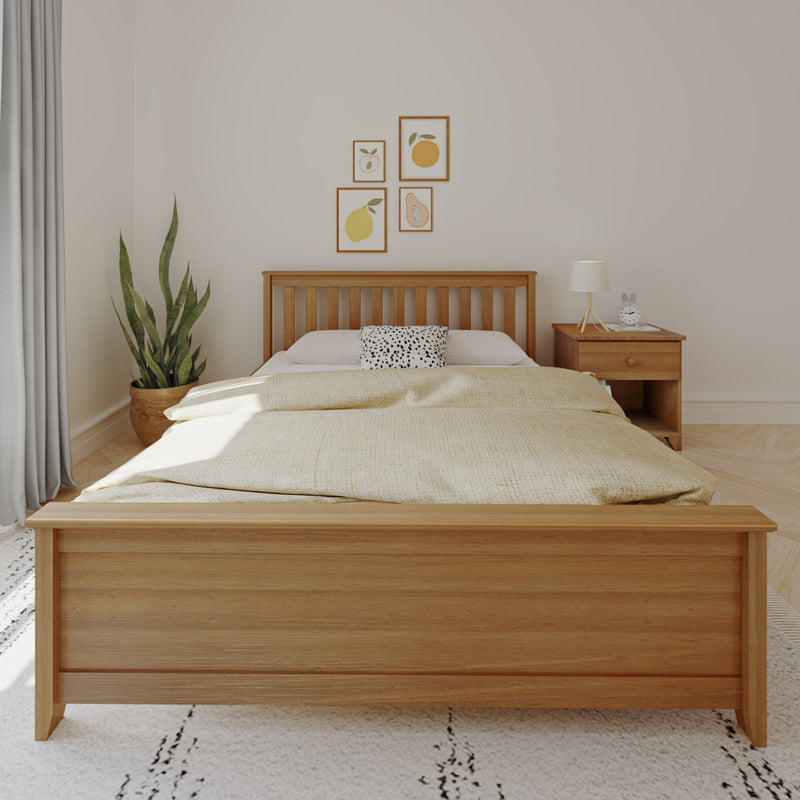 Minimalist neutral bedroom with wooden slat bed frame, beige linen bedding and spotted accent pillow, wooden nightstand with lamp and alarm clock, framed fruit prints and potted snake plant, modern Scandinavian decor