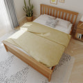 Scandinavian bedroom with wooden slatted bed frame, yellow duvet, black-and-white accent pillow, potted snake plant, bedside table and soft natural light