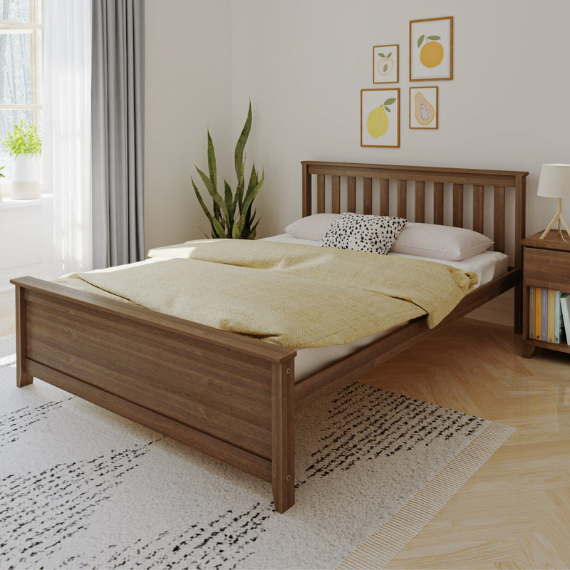 Wooden bed frame in modern bedroom with yellow bedding, houseplants, and framed wall art.