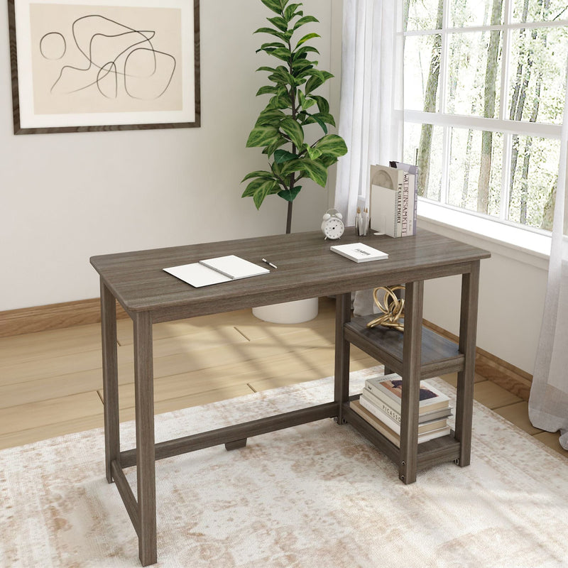 Gray-brown wood computer desk with built-in side shelves holding books and décor, notebook and pen on top, potted plant by sunlit window in a minimalist home office